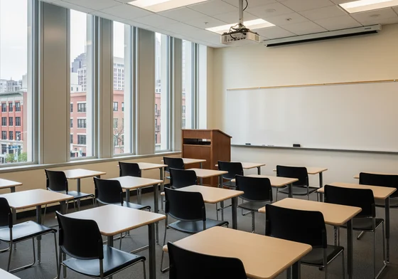 An empty college classroom with five rows of desks facing a blank whiteboard and a lectern.